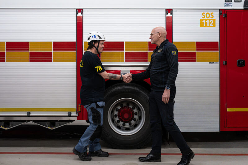 Roger och brandschefen Peter skakar hand framför en brandbil