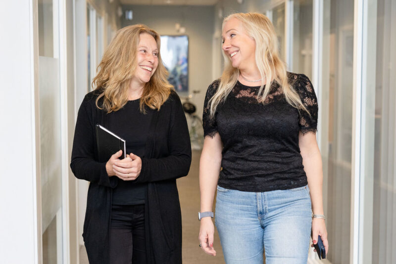 Två kvinnor går i en korridor och skrattar