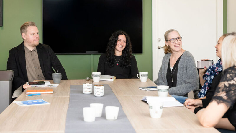 Tre kvinnor och en man sitter runt ett konferensbord