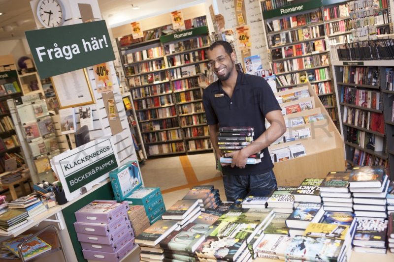 en man står i en bokaffär och ordnar med böckerna