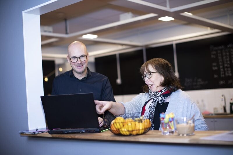 Två personer på Misa IT står framför en laptop och samtalar medan den ena pekar på skärmen