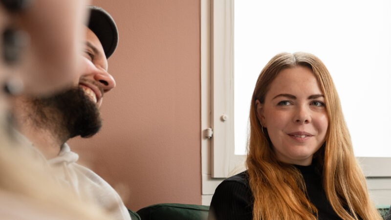 En person skrattar och en annan person med långt hår som sitter bredvid