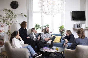 Flera personer sitter i en soffa och i fåtöljer och samtalar