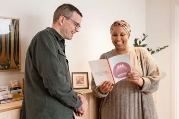 Två personer tittar i en broschyr och samtalar i Misas lokal