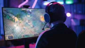 Dataskärm med en person framför som spelar dataspel